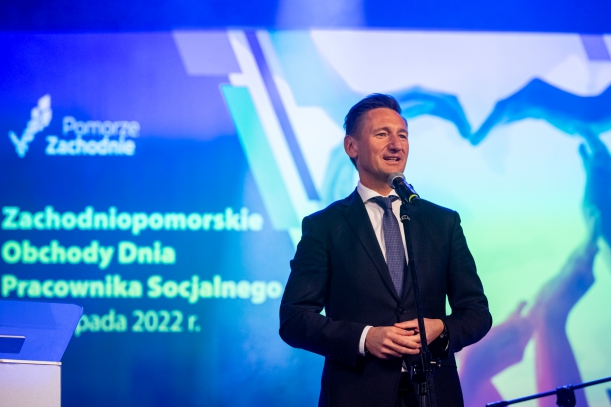 marszałek Olgierd Geblewicz przemawia na scenie, niebieskie tło