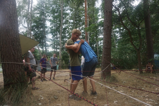 dwóch uczestników obejmując się wspólnie przechodzi przez poplątane w około drzew linki