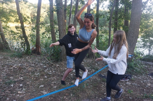 uczestniczka idzie po linie asekurowana przez kolegę i koleżankę