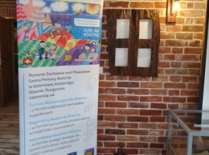 Roll-up projektu Kurs na Rodzinę postawiony w sali, w której odbywa się spotkanie podsumowujące dwa lata działań