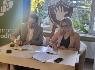 podpisanie umowy, dwie osoby, w tle roll-up z zielonym tłem, napis Pomorze Zachodnie