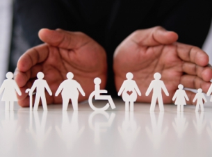 Dłonie obejmujące papierowe figurki ludzi w różnym wieku oraz różnym stanie zdrowie