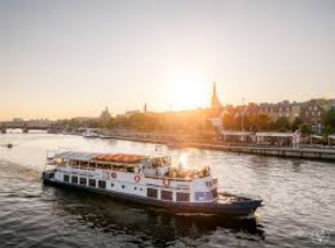 statek Odra Queen płynący nabrzeżem szczecińskiej części odry wtle zachodzącego słońca